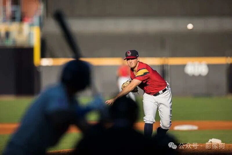ba<i></i>seball pitcher in red uniform mid-delivery, focused on batter