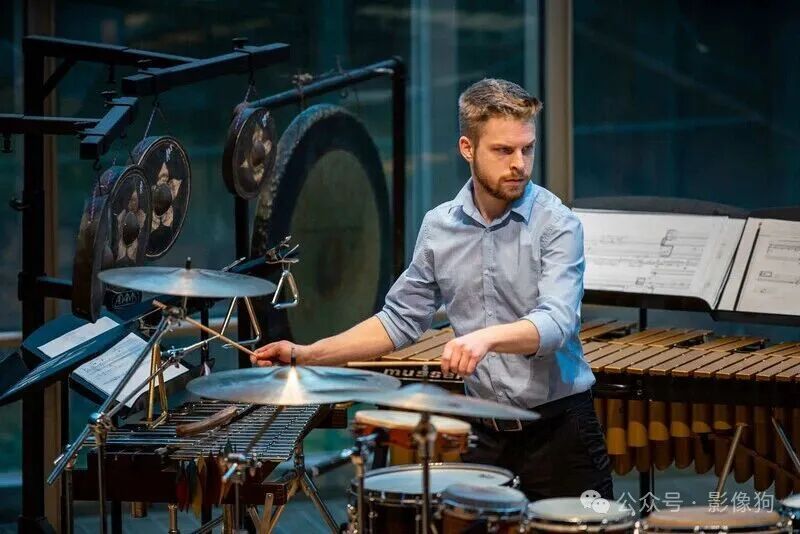 Musician playing vibraphone in studio with drums and keyboard visible